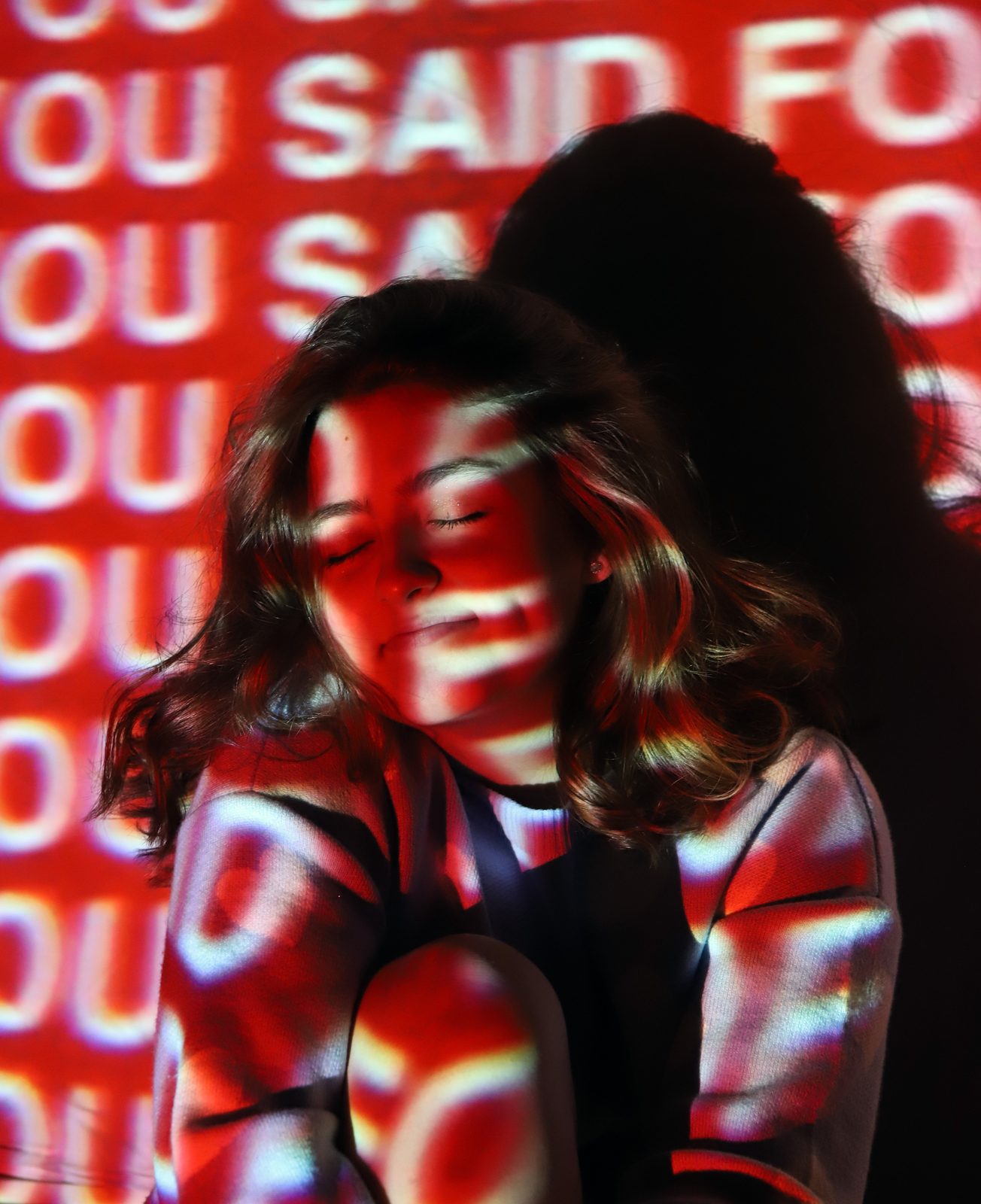 Portrait lit by red projected text falling across the subject and background